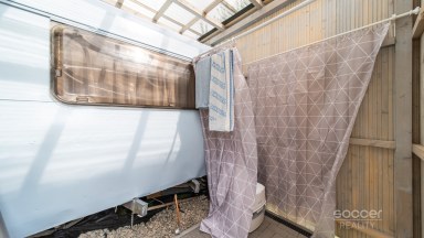 Příjemná venkovská zahrada s rekreačním karavanem a terasou.